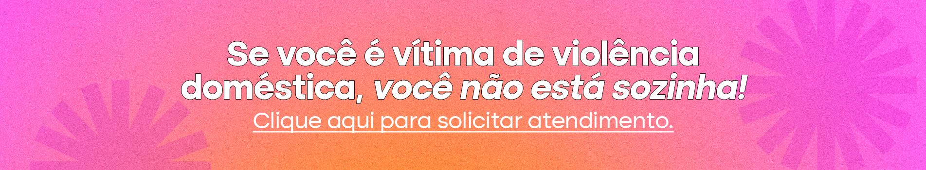 Botão para atendimento. Na imagem, um fundo em gradiente de rosa com laranja e, ao centro, o texto “Se você é vítima de violência doméstica, você não está sozinha! Clique aqui para solicitar atendimento".